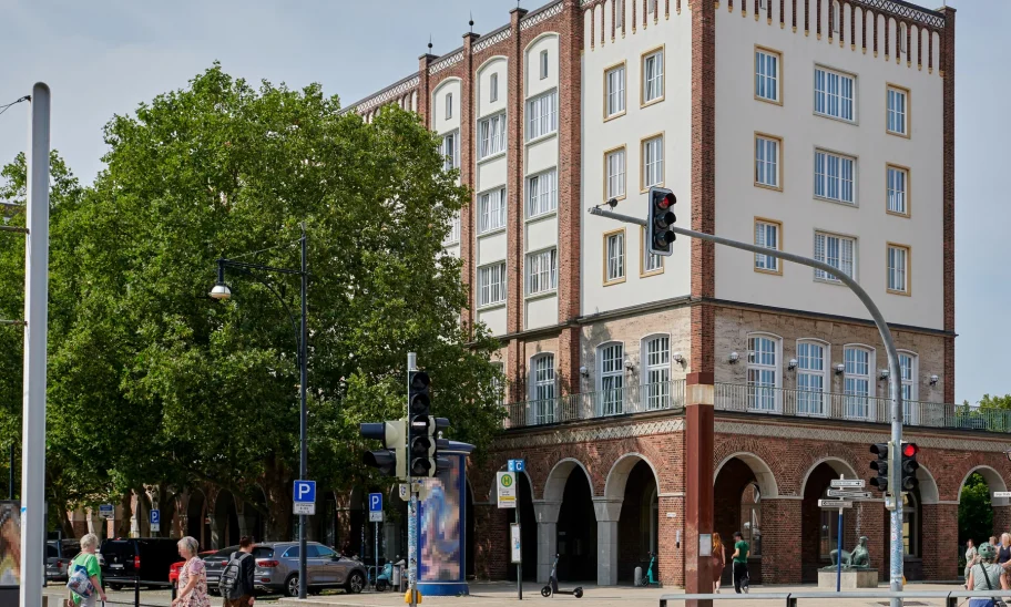Historisches Backsteingebäude mit Arkadengang und Staffelgiebel an einer Straßenkreuzung