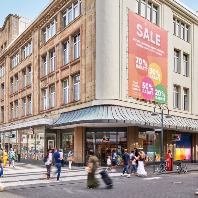 Eckgebäude mit Sale-Werbung und Fußgängerzone bei Sonnenschein