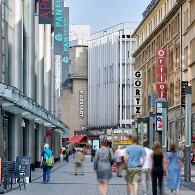 Einkaufsstraße mit Ladenschildern und Fußgängern vor dem Kaufhaus