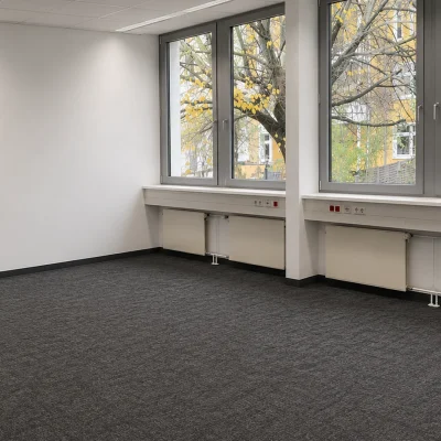 Leeres Büro im 1. Obergeschoss mit dunklem Teppichboden und großer Fensterfront