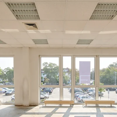 Leere Bürofläche im Rohzustand mit raumhoher Fensterfront und Blick auf den Parkplatz