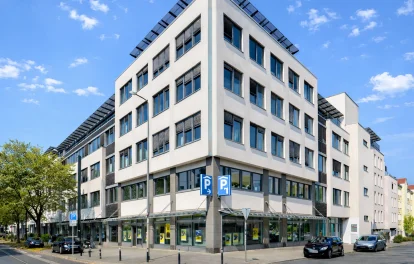 Markantes Eckgebäude mit Glasfassade, Dachterrasse und Ladenflächen im Erdgeschoss