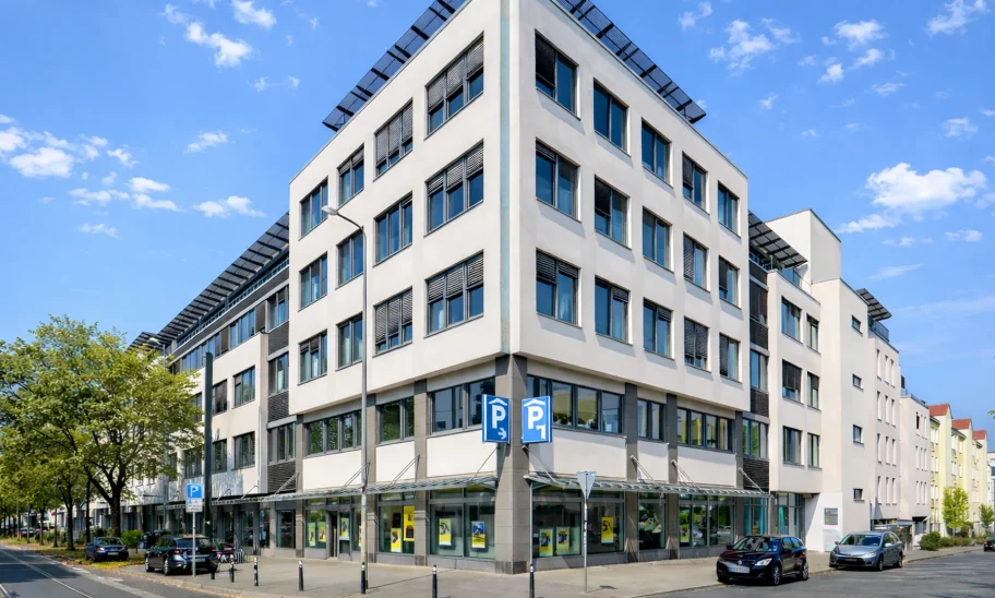 Markantes Eckgebäude mit Glasfassade, Dachterrasse und Ladenflächen im Erdgeschoss