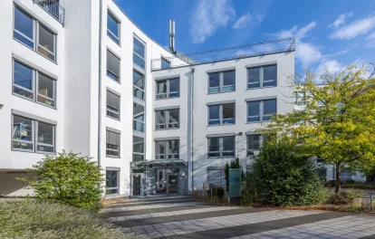 Eingangsbereich eines Bürogebäudes mit Glasvordach, geschwungener Fassade und verglastem Treppenhaus