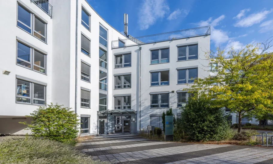 Eingangsbereich eines Bürogebäudes mit Glasvordach, geschwungener Fassade und verglastem Treppenhaus
