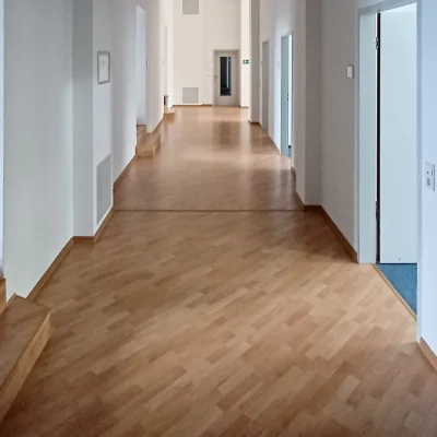 Langer Flur mit Holzboden, Stufen und mehreren Bürotüren