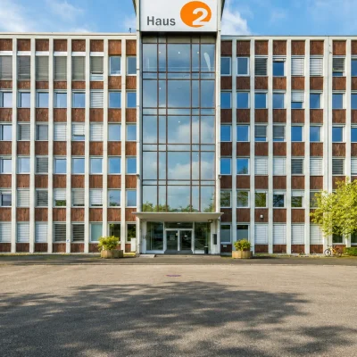 Frontalansicht von Haus 2 mit verglastem Treppenhaus und Vorfahrt