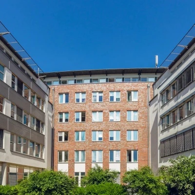 Innenhof mit rotem Backsteingebäude, grauen Fassaden und dichter Grünbepflanzung