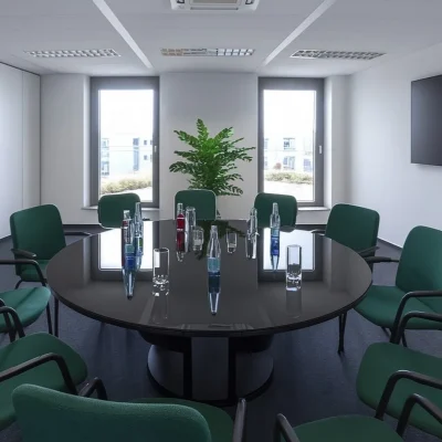 Runder Konferenztisch mit grünen Stühlen und Wandbildschirm im Besprechungsraum