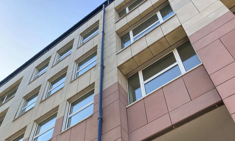 Fassadendetail mit beige-rosa Fliesen und Fensterreihen von unten fotografiert