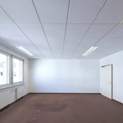 Leeres Büro mit Fensterfront, Teppichboden und Tür zum Flur