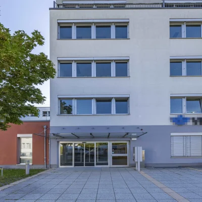 Bürogebäude mit rotem Sockelbau und überdachtem Eingangsbereich
