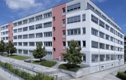 Weitwinkelansicht des Bürogebäudes mit rotem Fassadenakzent und Vorplatz