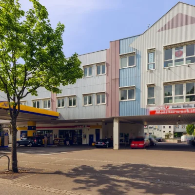 Gebäude mit bunter Fassade über einer Tankstelle mit Verkaufsshop
