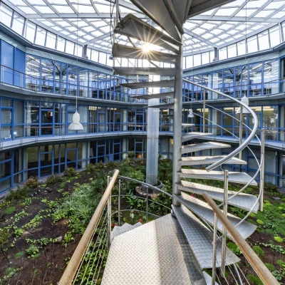 Nahaufnahme der Wendeltreppe im Atrium mit Sonnenlicht durch die Glaskuppel