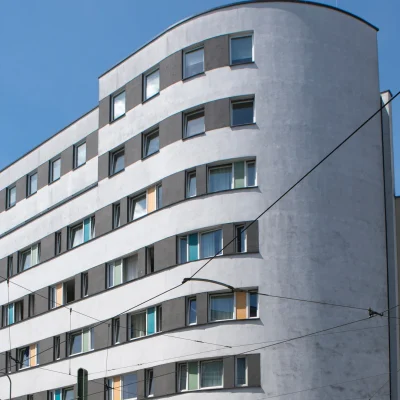 Hotelfassade mit abgerundeter Gebäudeecke und bunten Fensterakzenten vor blauem Himmel in Berlin