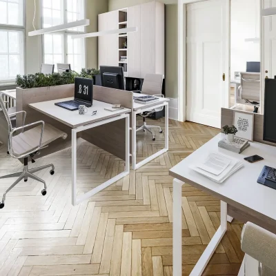 Büro mit Arbeitsplätzen, Pflanzenelementen, Fischgrätparkett und Schiebetür in einem Altbau mit hohen Fenstern