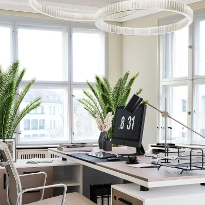 Einzelbüro mit Schreibtisch, Sideboard, Palmen und zwei Ringleuchten vor großen Sprossenfenstern