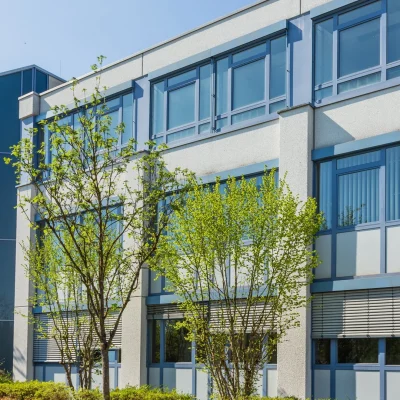 Fassade des Bürogebäudes DO3 mit blau gerahmten Fenstern, Glas-Treppenturm und jungen Bäumen davor