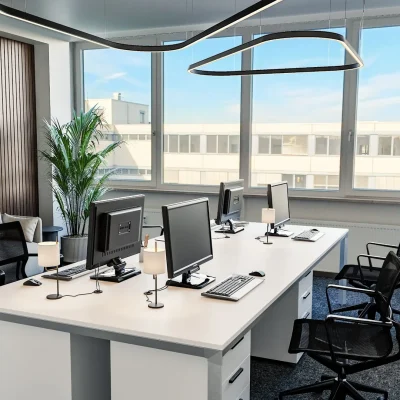 Büro im DO3 mit weißem Arbeitstisch, schwarzen Ringleuchten, Sofa und Bildschirm vor Holzlamellenwand (KI-Visualisierung)