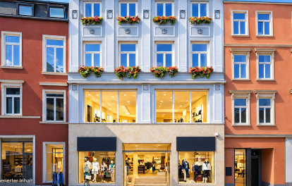 Hellgraue Altbaufassade mit Blumenkästen über Modegeschäft in der Rostocker Kröpeliner Straße