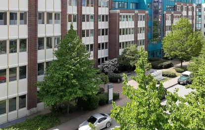 Backsteinfassade mit türkiser Dachkante und begrüntem Innenhof des Bürogebäudes in Hamburg