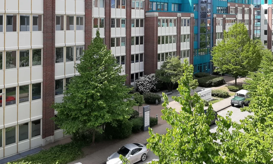 Backsteinfassade mit türkiser Dachkante und begrüntem Innenhof des Bürogebäudes in Hamburg