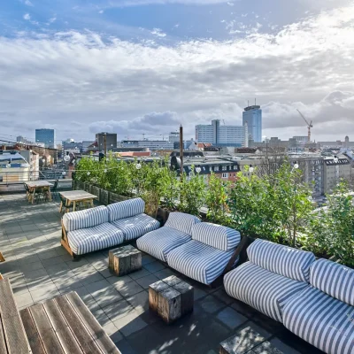 Dachterrasse mit gestreiften Loungemöbeln, Holzschaukel und Blick auf den Berliner Fernsehturm