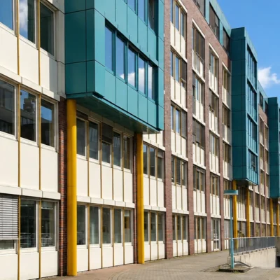 Bürogebäude mit gelben Stützen, türkisen Fassadenelementen und Zufahrt zur Tiefgarage
