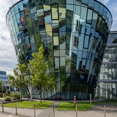Weißer Gebäudeeingang mit moderner Skulptur auf der Rasenfläche