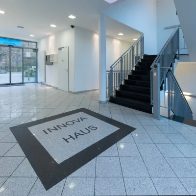 Eingangsfoyer mit Treppenhaus und Bodeninschrift 'Innova Haus'