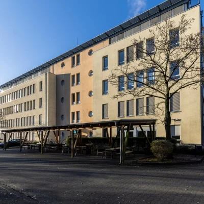 Mehrstöckiges Bürogebäude mit überdachtem Sitzbereich und Parkplatz