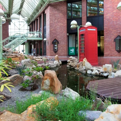 Atrium mit Teich, Steinen, Pflanzen und roter Telefonzelle