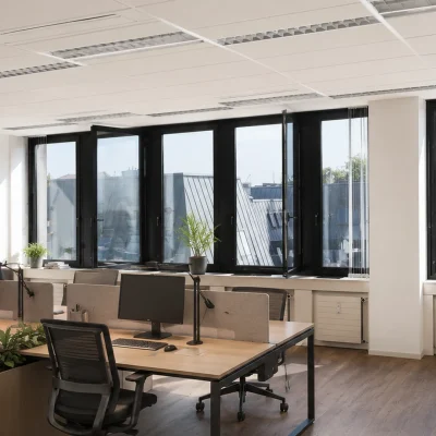 Open-Space-Büro mit Schreibtischen, Kippfenstern und Dachblick