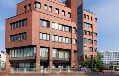 Straßenansicht des Bürogebäudes mit Backsteinfassade und Alleebaum