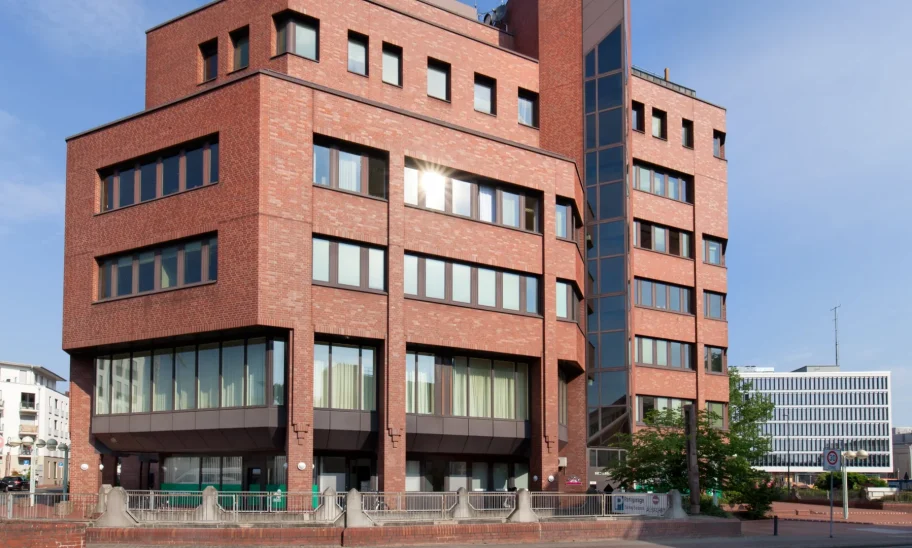 Straßenansicht des Bürogebäudes mit Backsteinfassade und Alleebaum