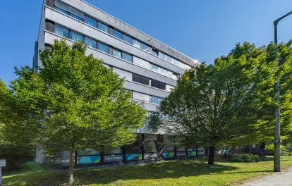 Bürogebäude 'Hexagon' mit Bäumen und bunter Fassadenbeschriftung