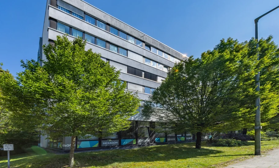 Bürogebäude 'Hexagon' mit Bäumen und bunter Fassadenbeschriftung
