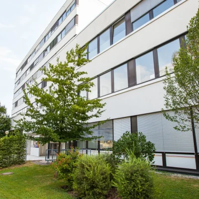 Weißes Bürogebäude mit Bäumen und Piepenbock-Firmenschild
