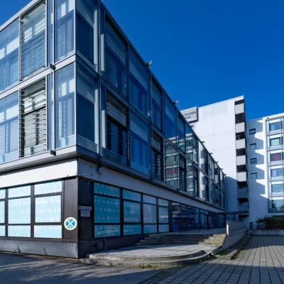Glasfassade des Bürogebäudes mit Lamellenfenstern vor blauem Himmel