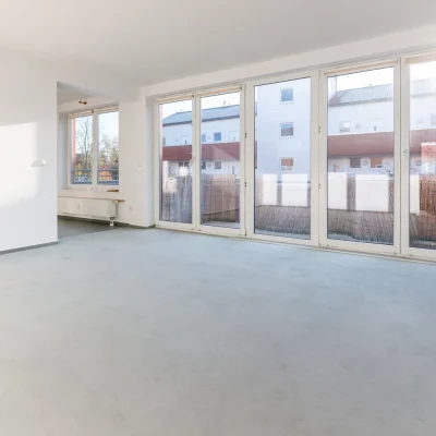 Leerstehende Büro-/Wohnfläche mit großer Fensterfront und Balkonzugang