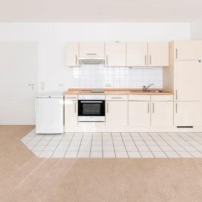 Einbauküche mit cremefarbenen Schränken, Herd und Kühlschrank