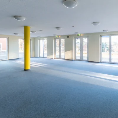 Leerstehende Gewerbefläche mit gelber Stütze und Terrassenzugängen