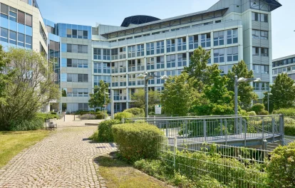 Bürogebäude mit markanter Eckfassade und begrüntem Vorplatz