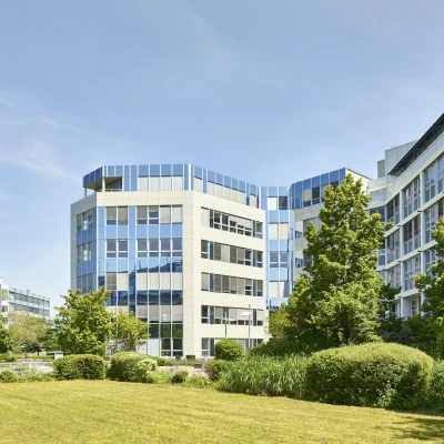 Weitwinkelansicht des Bürogebäudes mit Rasenfläche und Bäumen