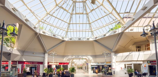 Das Bild zeigt das Innere eines Einkaufszentrums in Krefeld mit großer Glaskuppel, Cafés, Restaurants und verschiedenen Ladengeschäften.