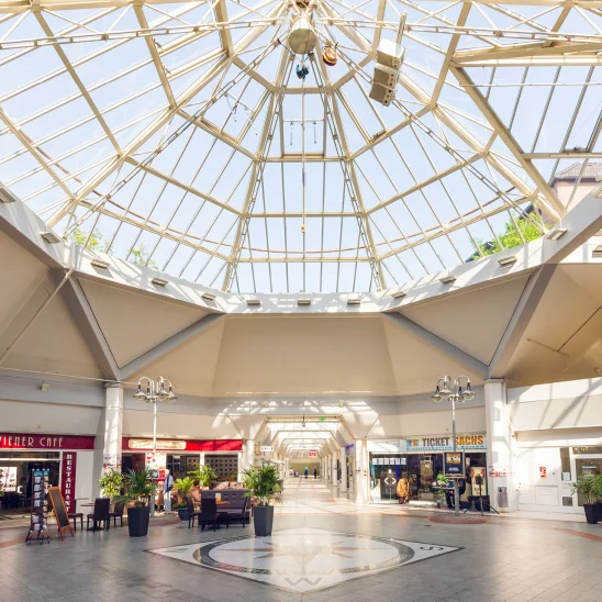 Das Bild zeigt das Innere eines Einkaufszentrums in Krefeld mit großer Glaskuppel, Cafés, Restaurants und verschiedenen Ladengeschäften.